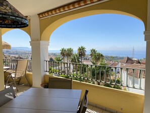 Enjoy the serene view of the surrounding landscape from this balcony with a table and chairs.