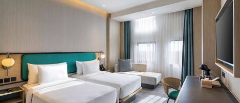 Habitación de hotel con dos camas, un escritorio, una silla, un televisor y una ventana con cortinas.
