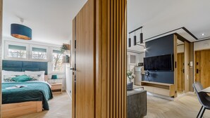 A modern bedroom with a large bed, a desk, and a TV. - Mokotów Sobieskiego (Warsaw)