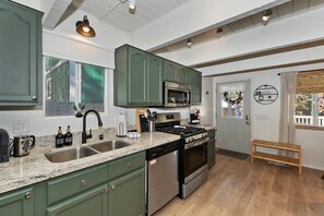Une cuisine avec des meubles de couleur verte, une cuisinière en acier inoxydable et un lave-vaisselle.