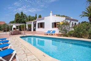Uma villa branca com piscina, área de estar externa e jardim.