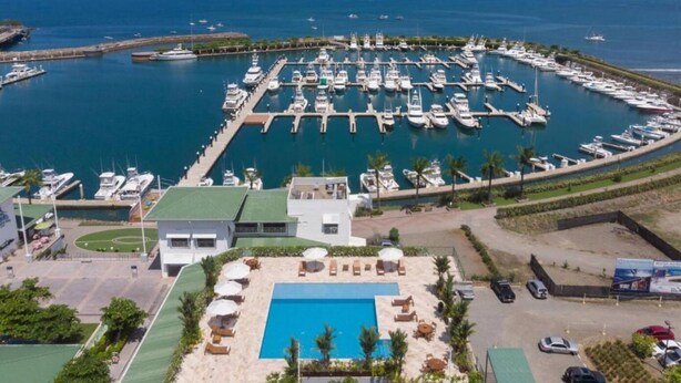A marina with numerous boats docked, a swimming pool, and a view of the sea. - Near Manuel Antonio-Private Pool-Gated-Chic-Paved road-minutes to marina (San Martin)