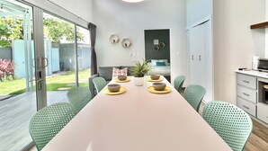 A modern kitchen with a dining area, featuring a long table with chairs, a microwave, and a coffee machine. - Near Manuel Antonio-Private Pool-Gated-Chic-Paved road-minutes to marina (San Martin)