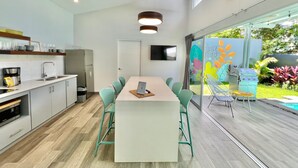 A modern kitchen with a central island, built-in appliances, and a large window overlooking a garden. - Near Manuel Antonio-Private Pool-Gated-Chic-Paved road-minutes to marina (San Martin)