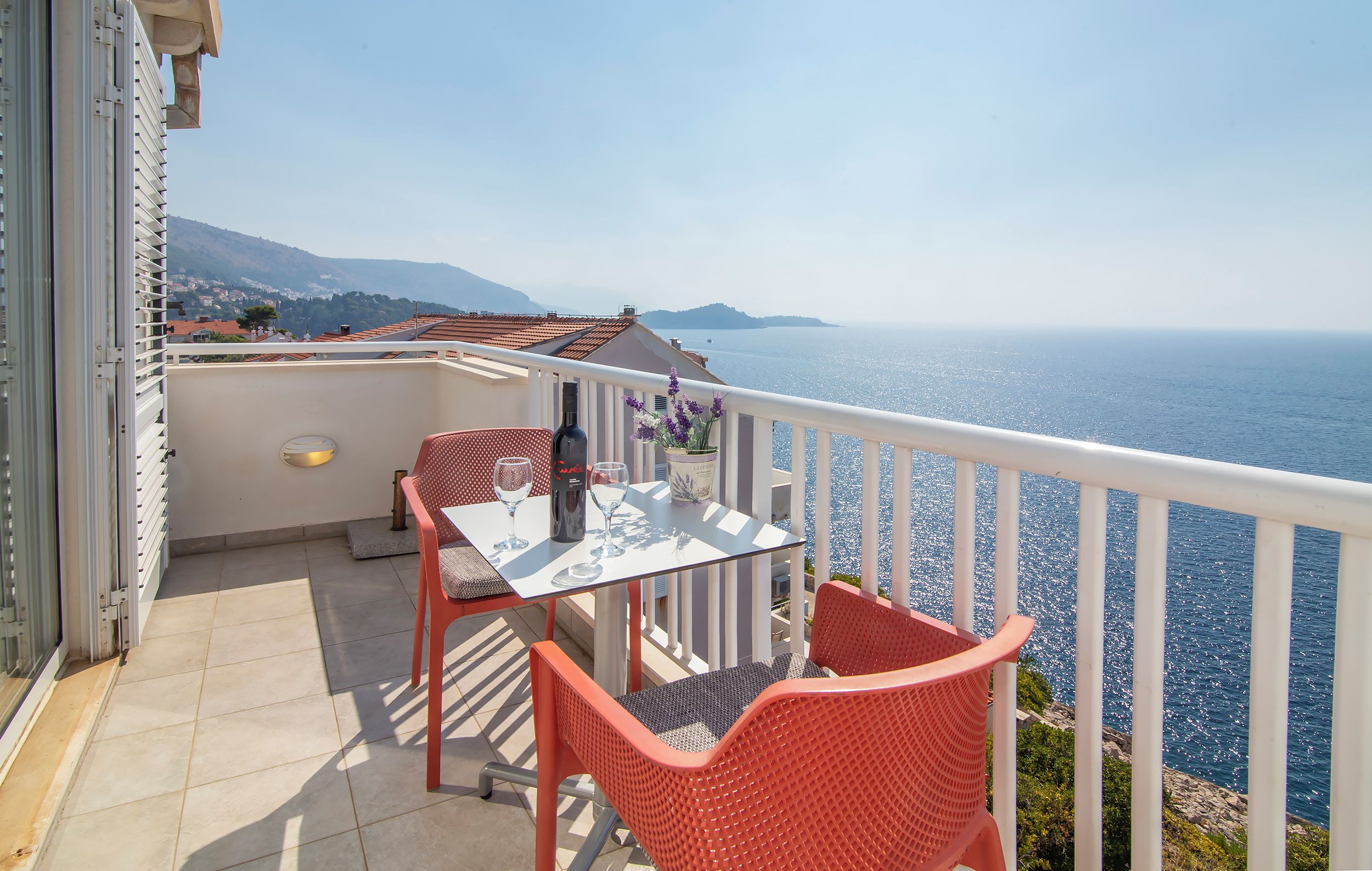 A balcony with a table and chairs, overlooking a body of water.