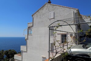Un edificio con balcón y vistas al mar, con un coche estacionado.