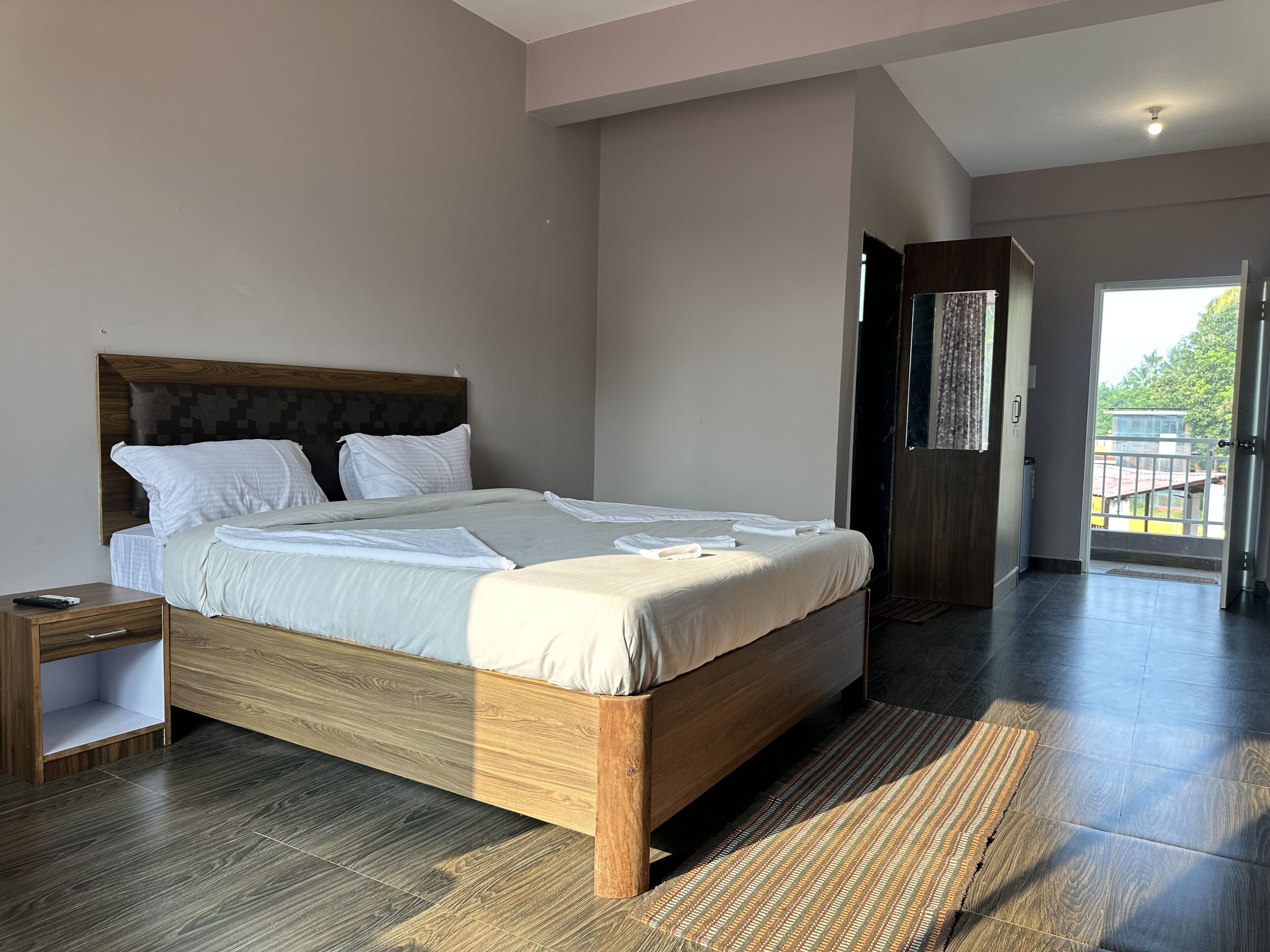 Un dormitorio moderno con una cama grande, cabecera de madera y vistas al exterior a través de una puerta.