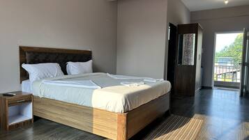 Un dormitorio moderno con una cama grande, cabecera de madera y vistas al exterior a través de una puerta.
