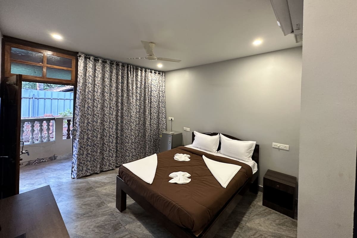 A hotel room with a bed, a ceiling fan, a window with curtains, and a view of the outside.