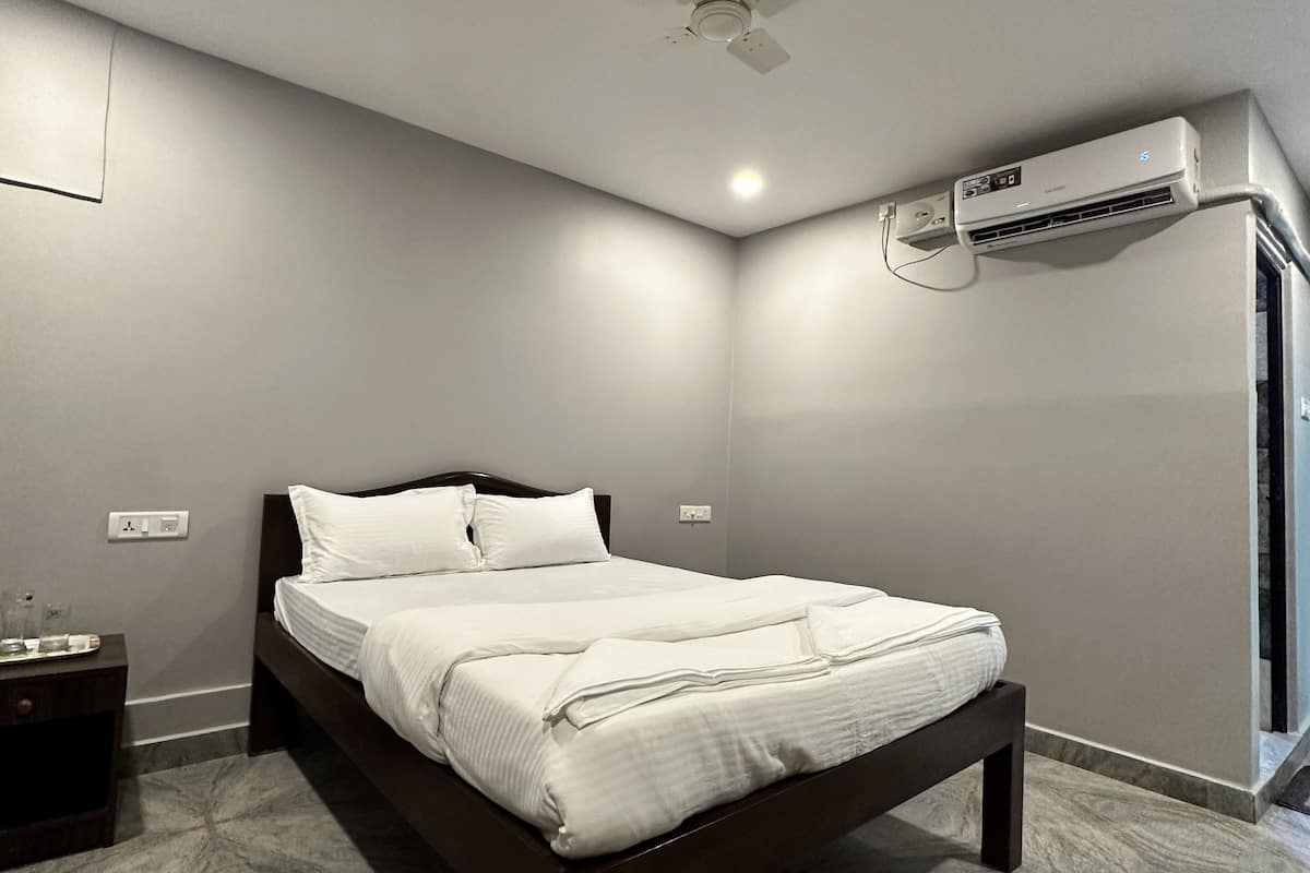 A modern bedroom with a bed, a ceiling fan, an air conditioning unit, and a marble-patterned floor.