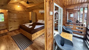 Una habitación de cabaña de madera con una cama, una mesita pequeña y una silla.