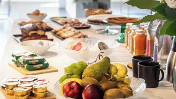 Una mesa de buffet con diferentes alimentos, como frutas, pasteles y salsas.