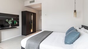 A modern bedroom with a bed, bedside tables, a wardrobe, and a wall-mounted TV. - Feudo Antico (Tollo)