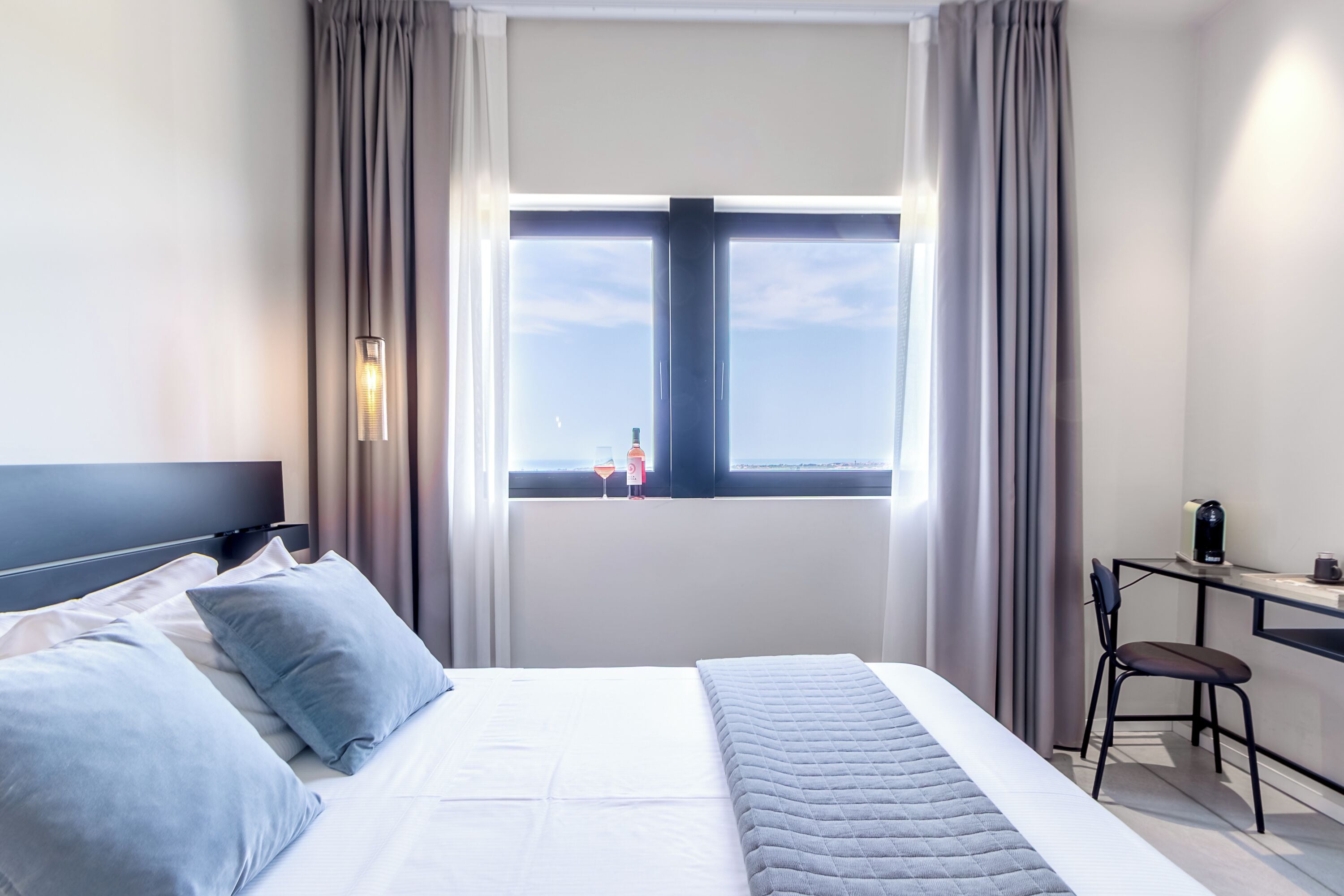 A hotel room with a bed, a desk, a chair, a window with a view, and a television.