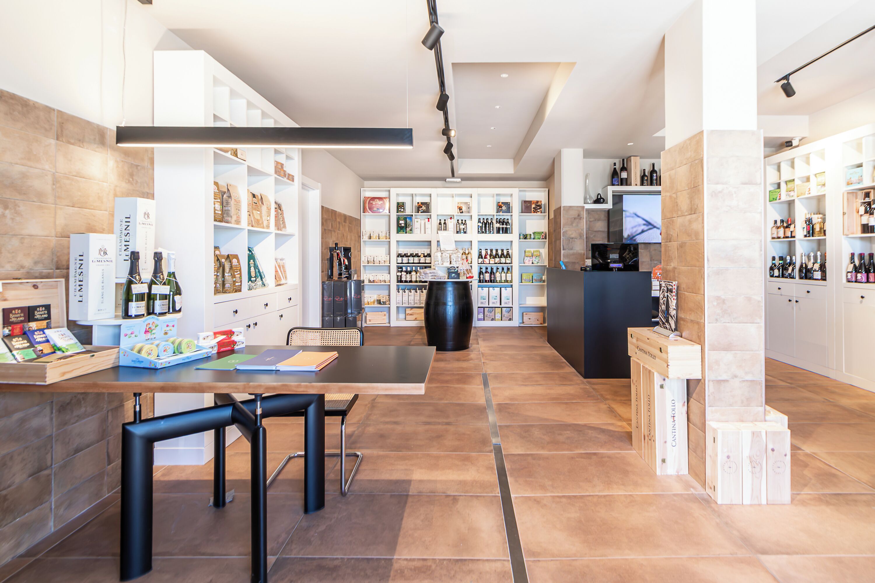 Un interior moderno con una mesa central, sillas y estanterías llenas de diversos objetos.