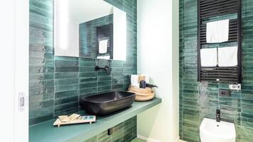 A bathroom with a large mirror, a black basin, a white sink, and a towel rack.