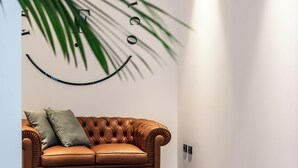 A brown leather sofa with two cushions against a white wall with a smiley face design. - Feudo Antico (Tollo)