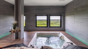 A modern spa room with a hot tub, large windows, and a view of the countryside. - Feudo Antico (Tollo)