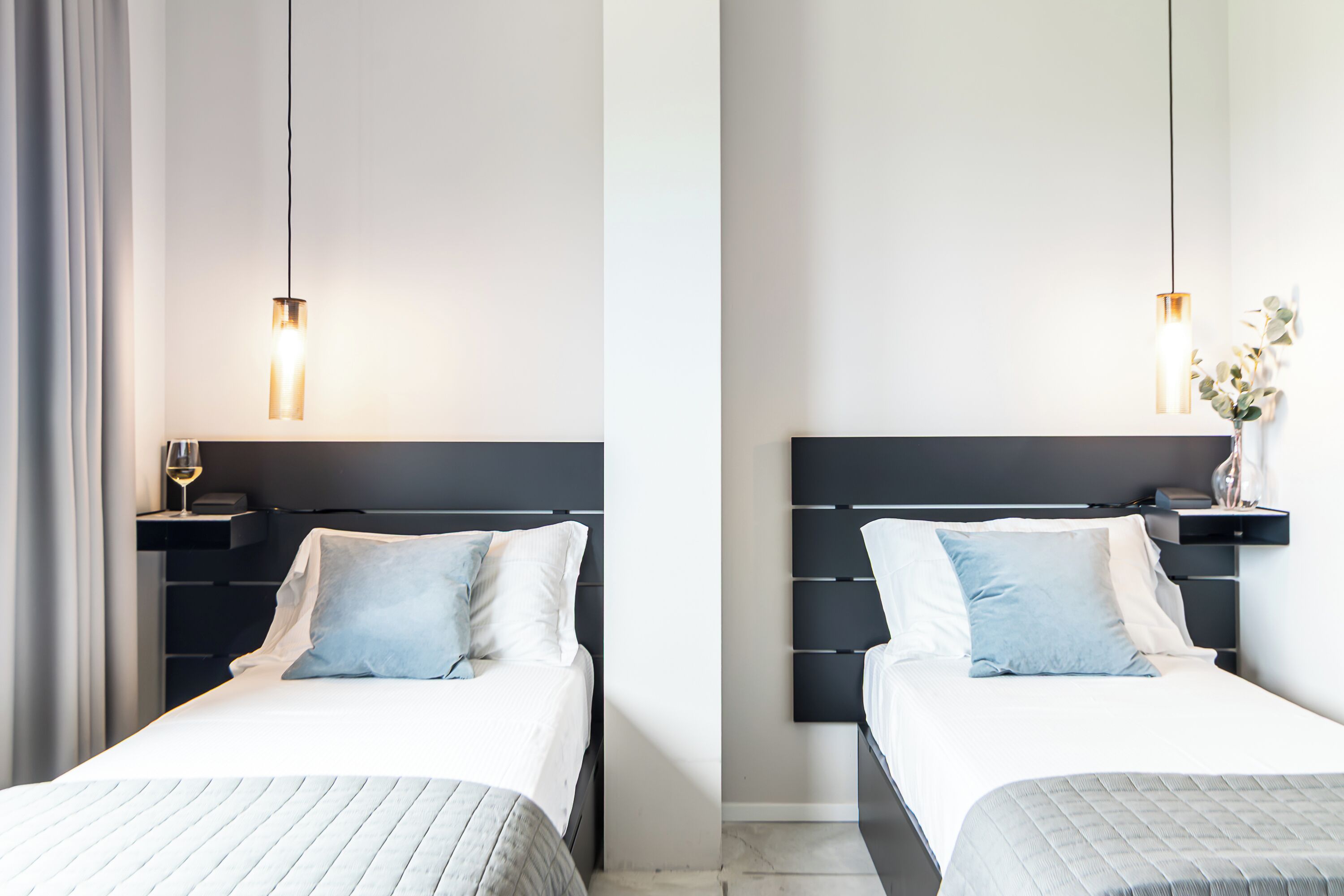 A hotel room with two beds, each with a headboard, bedside tables, and a lamp.