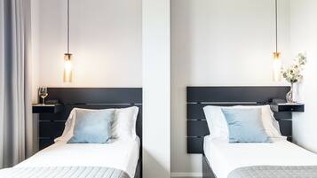 A hotel room with two beds, each with a headboard, bedside tables, and a lamp.
