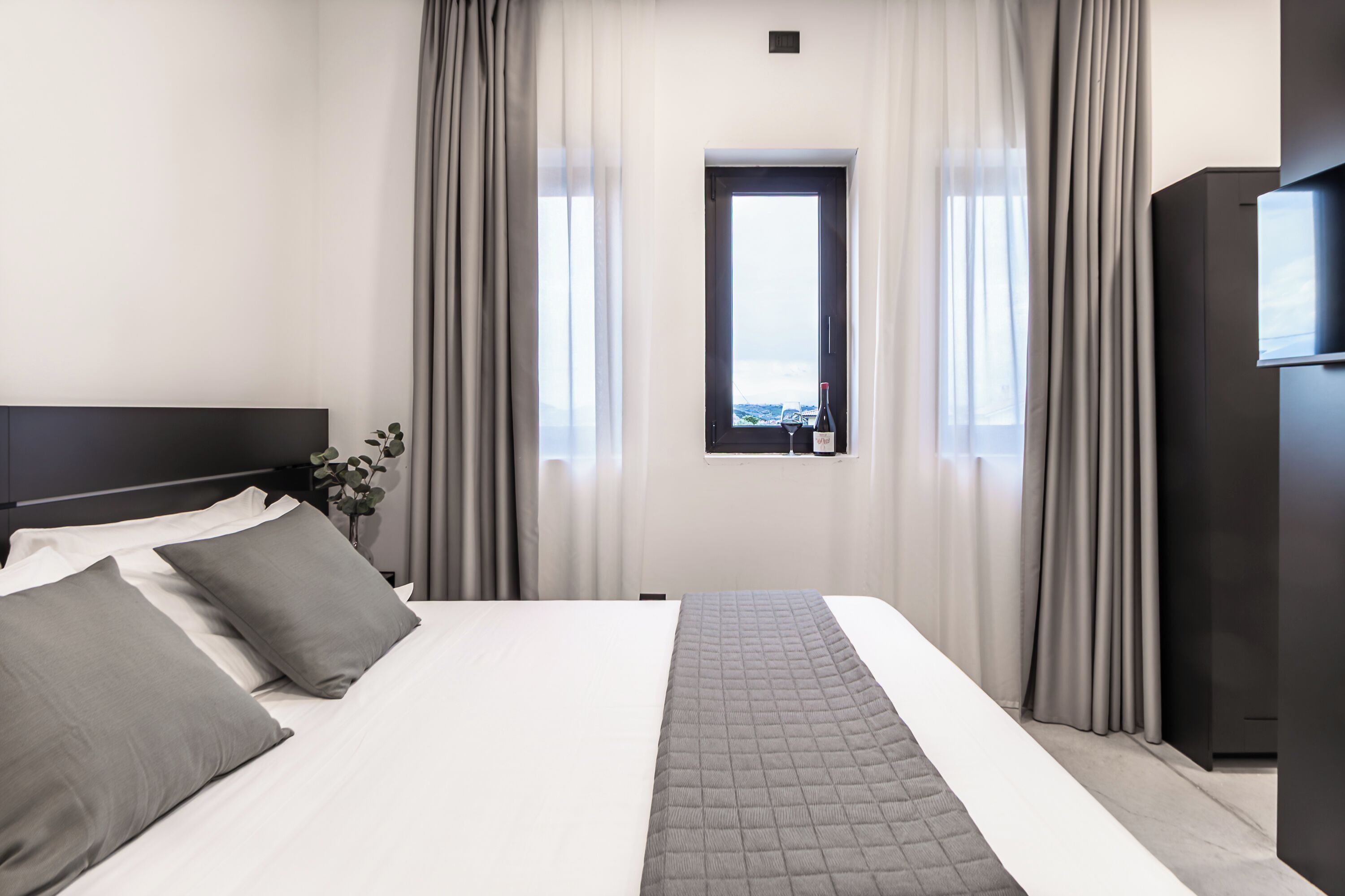 Una habitación de hotel con cama, cortinas, una ventana y vistas.
