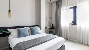 Una moderna camera d'albergo con un letto, una scrivania e una finestra con tende.