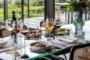 A table set for a meal with various dishes and glasses of wine, overlooking a garden. - Feudo Antico (Tollo)
