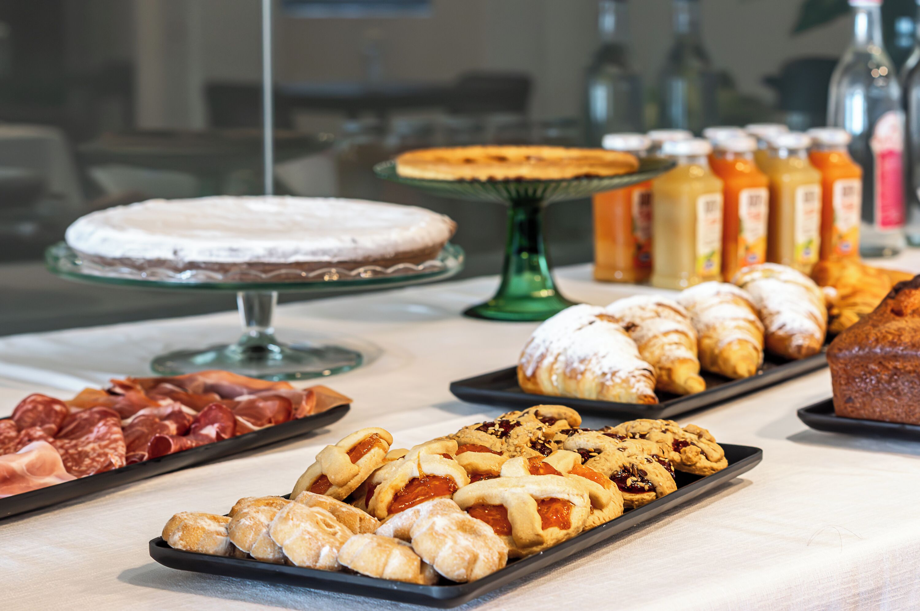Un bufé con diversas opciones de comida, incluyendo pasteles, una tarta y una selección de carnes.