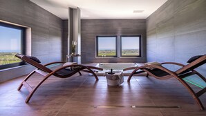 A modern spa room with two lounge chairs, a bathtub, and a view of the countryside. - Feudo Antico (Tollo)