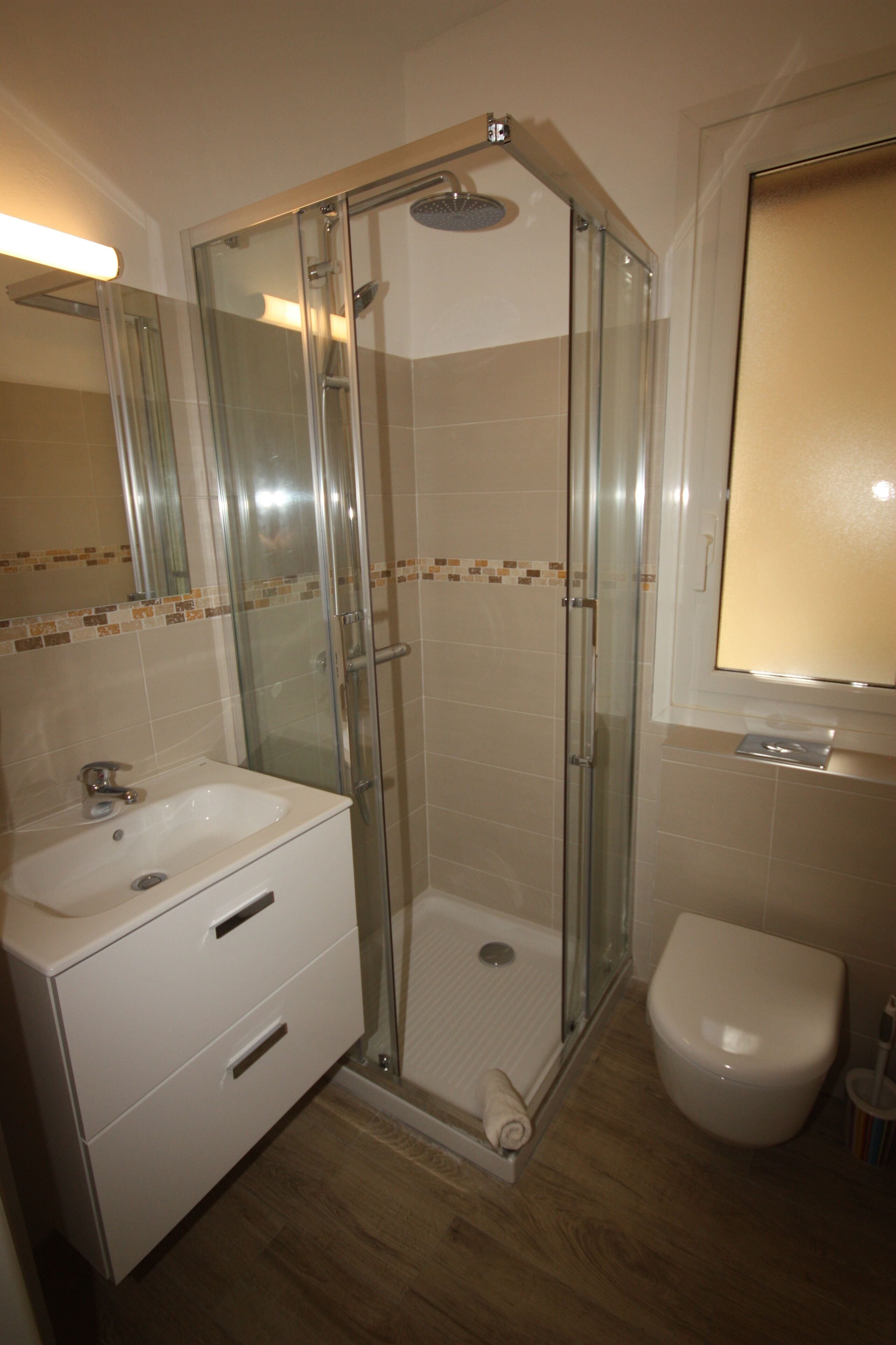 A modern bathroom with a glass-enclosed shower, a white sink, and a toilet.