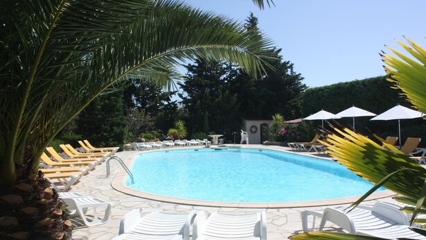 Ein Schwimmbad mit Liegestühlen und Sonnenschirmen.