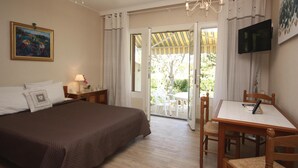 Ein Hotelzimmer mit Bett, Tisch, Stühlen, Fernseher und Blick ins Freie.
