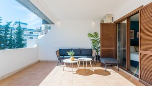Un balcon avec un canapé, deux tables et une plante en pot.