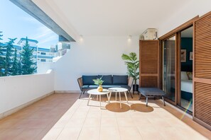 A balcony with a sofa, two tables, and a potted plant. - Balaia apartment at Albufeira (Albufeira)