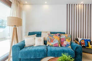 A modern living room with a blue sofa, patterned cushions, a floor lamp, and a striped wall. - Balaia apartment at Albufeira (Albufeira)