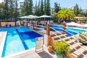 A swimming pool with a wooden deck, lounge chairs, and umbrellas. - Balaia apartment at Albufeira (Albufeira)