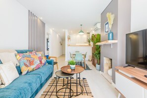 A modern living room with a blue sofa, a coffee table, and a TV on a wooden stand. - Balaia apartment at Albufeira (Albufeira)