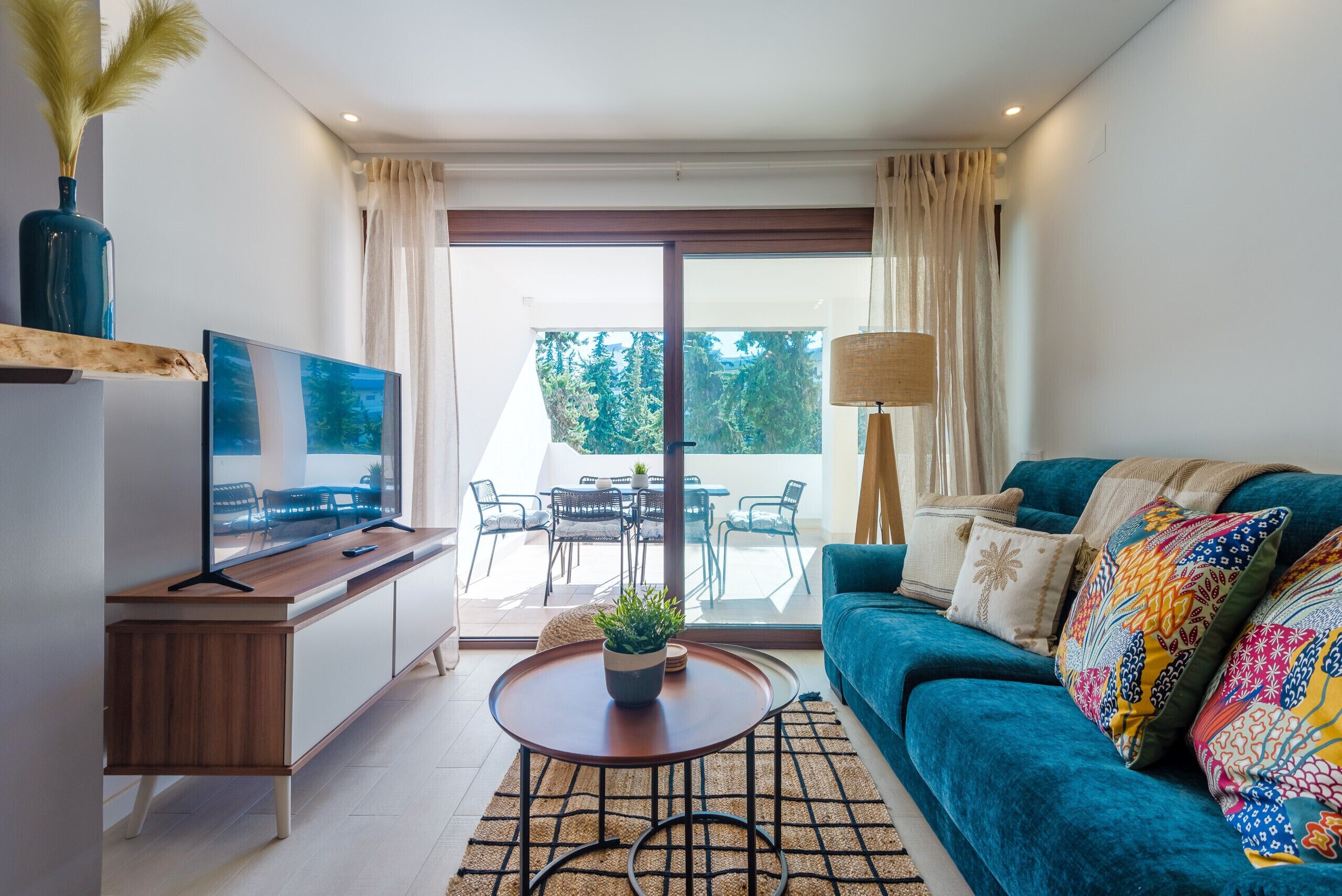 A modern living room with a television, sofa, coffee table, and a view of the outdoors.