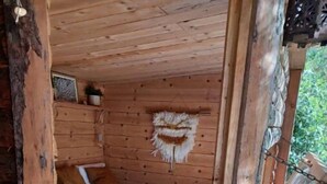 Una cabaña de madera con una cama, un adorno colgante en la pared y vistas al exterior.