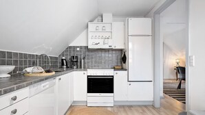A modern kitchen with white cabinetry, a built-in oven, a refrigerator, and a coffee maker. - 1 bedroom amazing apartment in Mariager (Mariager)