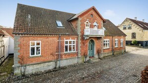 A red brick house with a white balcony, a green door, and a cobblestone courtyard. - 1 bedroom amazing apartment in Mariager (Mariager)