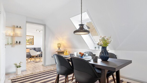 A modern dining area with a dark wooden table, black chairs, and a blue vase with flowers. - 1 bedroom amazing apartment in Mariager (Mariager)