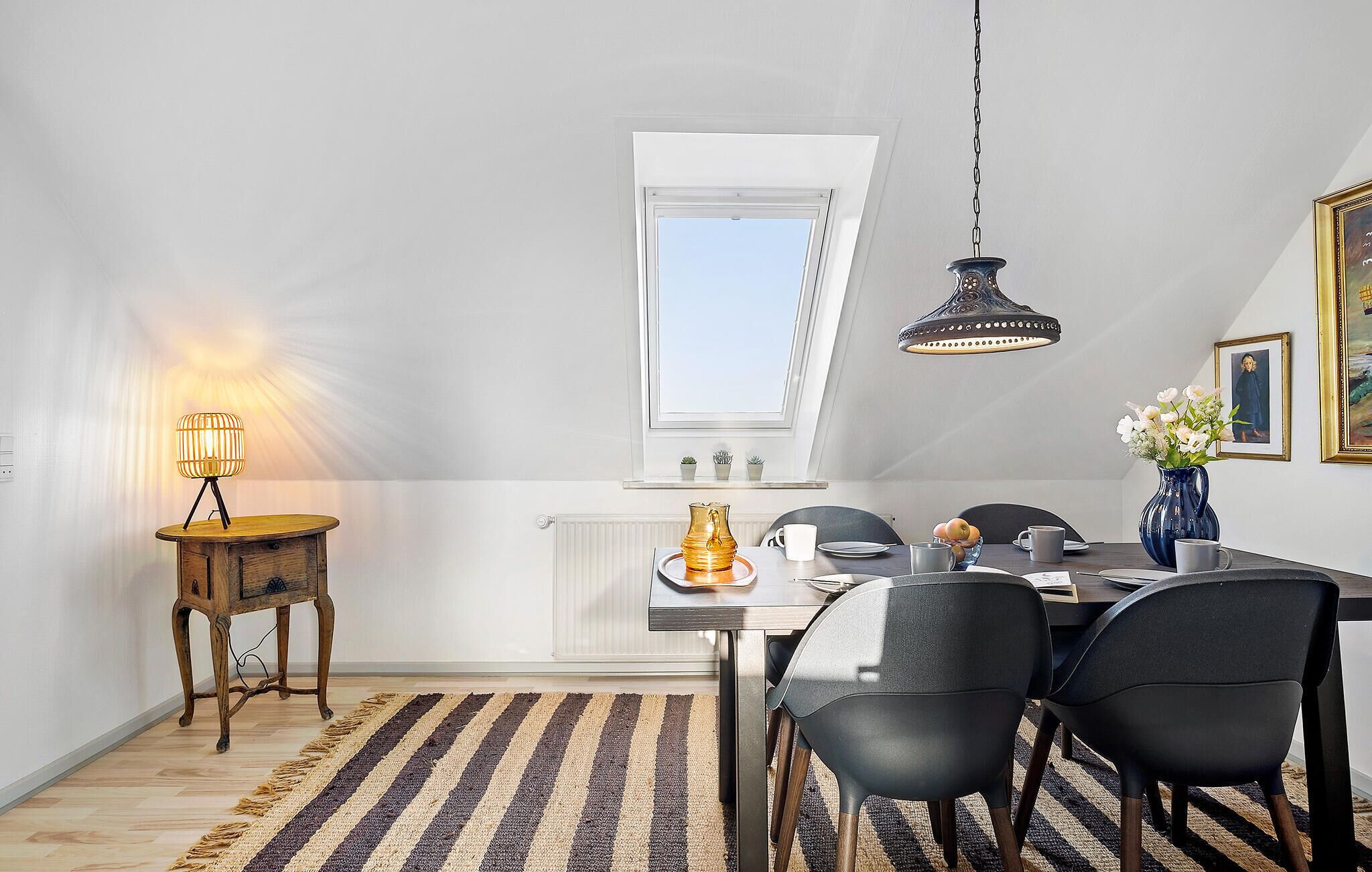 A dining area with a table, chairs, a lamp, and a hanging light fixture.