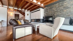 Una sala de estar con chimenea, televisor y pared de piedra.