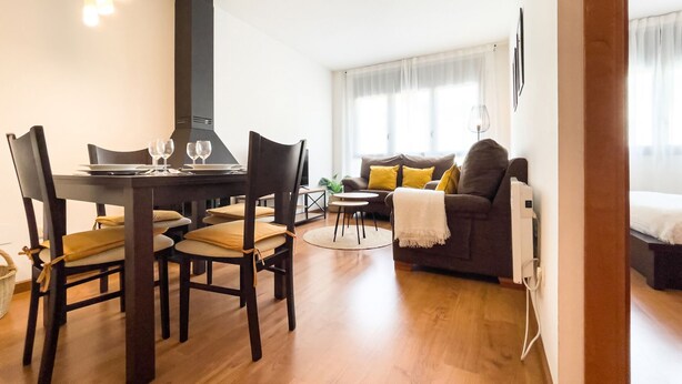 Uma sala de estar moderna com área de jantar, apresentando um sofá, uma mesa de centro e uma mesa de jantar com cadeiras.