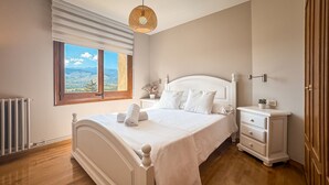 A bedroom with a bed, bedside table, nightstand, and a window with a view. - Cal Gatesques 1 (Puigcerda)
