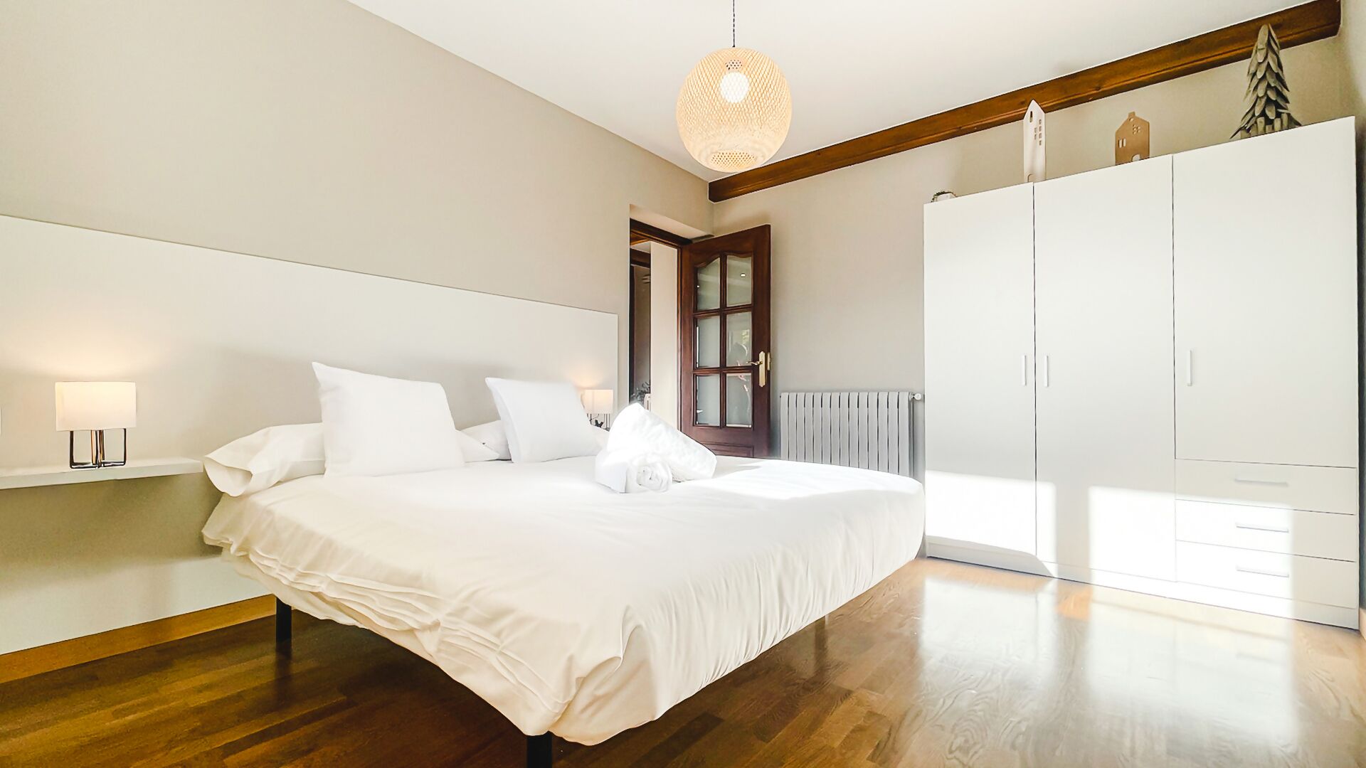 Un dormitorio con una cama grande, un armario, un radiador y una lámpara colgante.