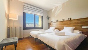 Habitació d'hotel amb dos llits, una taula de nit, una làmpada i una finestra amb vistes.