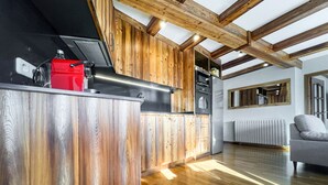 Una cuina moderna amb detalls de fusta, un aparell vermell i una finestra gran.
