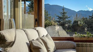 Un salon avec un canapé et une porte vitrée donnant sur une vue sur la montagne.